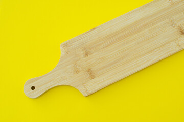 Wooden or bamboo cutting board on a yellow background, copy space