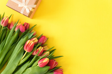spring flowers a bouquet of pink and yellow tulip with gifts on a yellow background....
