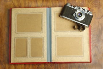 Old photo album and film camera on a wooden table. Copy space.