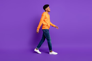 Fototapeta na wymiar Full length body size profile side view of attractive cheerful guy strolling isolated over bright violet purple color background