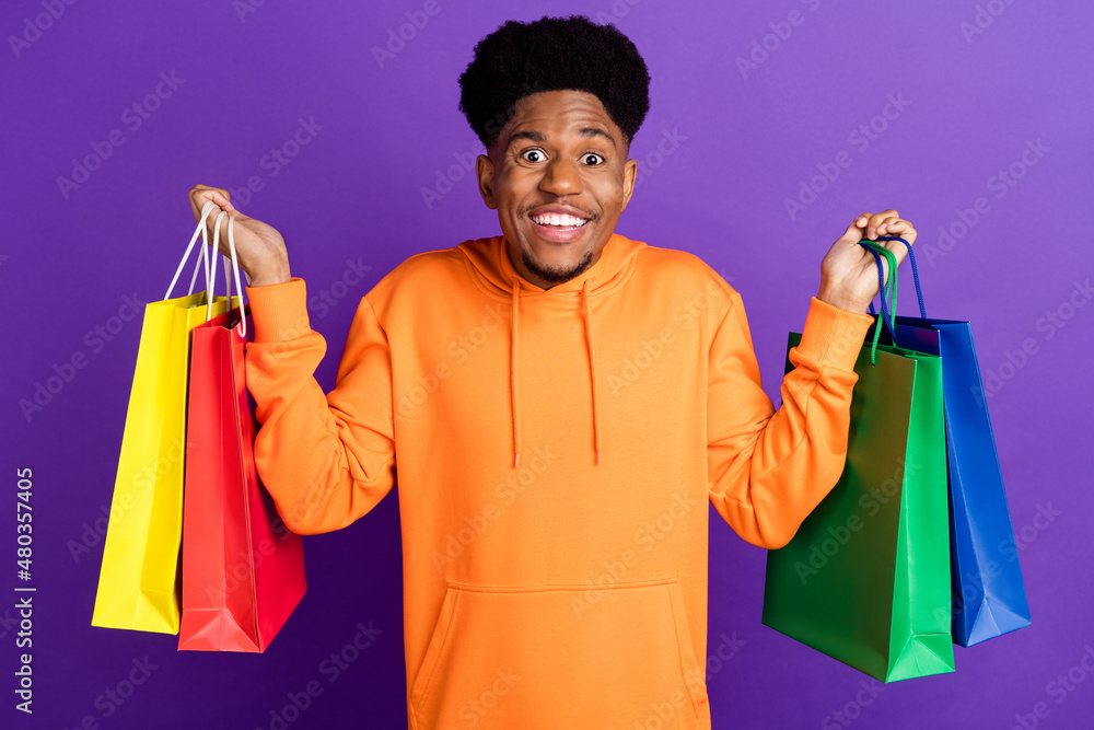 Wall mural Photo of young black man happy positive smile hold shopping bags black friday customer isolated over violet color background