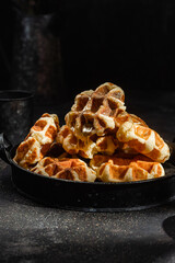 Belgian waffles with honey on a dark background