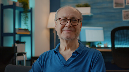 Portrait of senior adult looking at camera in living room, dealing with chronic disability and injury. Retired man with medical equipment to help with transportation and accessibility.