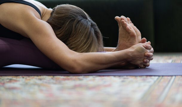 Woman Practices Yoga Asanas in Morning for Energy for the Whole Day. Yoga Lady Doing Seated Forward Bend Exercise Face Down. Close-up