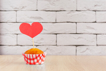Sweet vanilla cupcake decorated red heart on wood table and concrete backgroud. Concept Valentine's Day