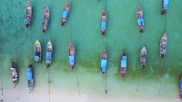 Aerial view of stunning summer landscape. A group of fishing long tail boat in turquoise Andaman sea and white sand beach at Koh Lipe or Lipe island, Satun, Southern Thailand. 4K drone video