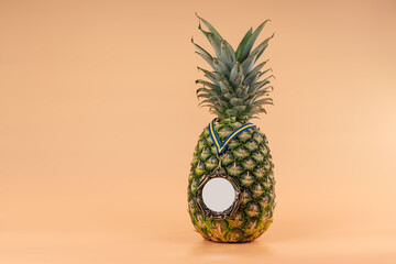 Interpretation of the pineapple fruit into a human image with a medal as a symbol of victory, success and strength. On a yellow background.