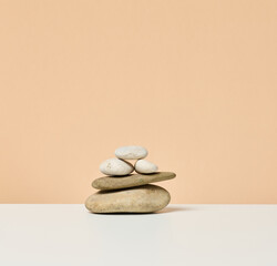 stack of round stones on a beige background. Scene for demonstration of cosmetic products, advertising