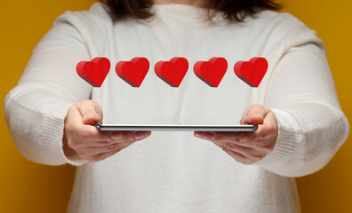 woman holds an electronic tablet and five red hearts over it. Feedback concept, business rating