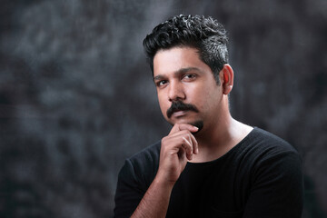 Portrait of a young Indian against a dark grey background