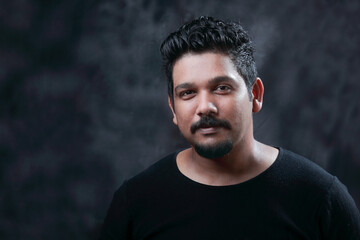 Portrait of a young Indian against a dark grey background