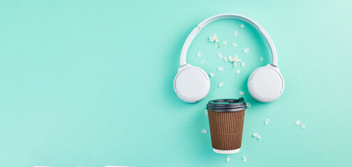 Obraz premium Music or podcast banner with headphones with cherry blossom on turquoise background. flat lay. Top view. Spring playlist concept