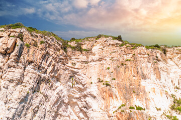 Fototapeta na wymiar Layered rocky cliffs with plants near shore of Corfu island