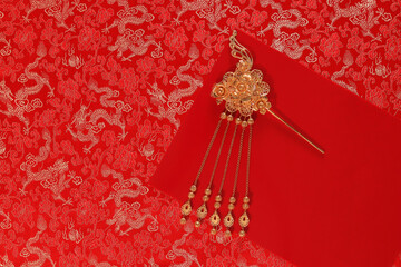 Red fabric with dragon pattern with red copy space for text and golden female hairpin. Concept of...