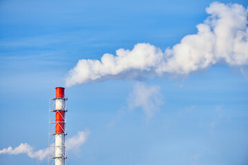 Obraz premium Smoke exhausting from chimney. Huge smoke from the pipe. Red-white chimney of factory. Environmental pollution. Carbon dioxide emissions. Global climate protection concept.