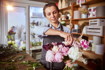 Florist arranging pink bouquet at flower shop