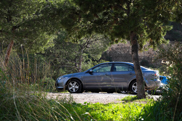 A car in an open-air parking lot in the countryside, of a family who has come to hike