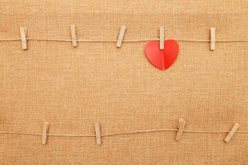 red heart on clothes pin on brown textile background