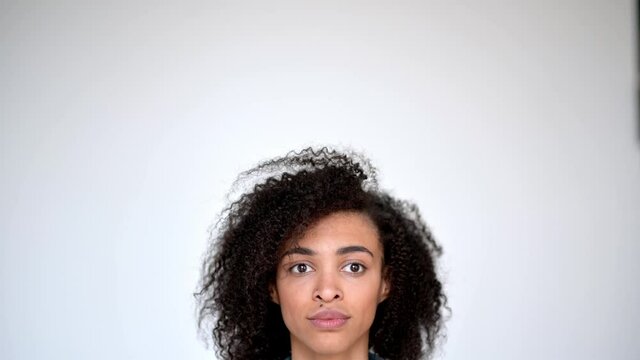 Happy lovely millennial african american curly girl, points with hands up to empty space, looks at camera, smiling friendly, on isolated background in casual clothes
