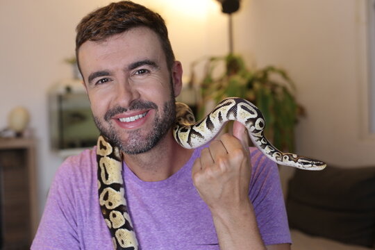 Cute man holding exotic ball python   