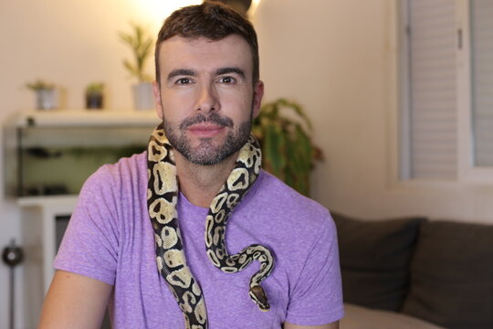 Cute man holding exotic ball python   