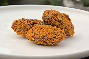 Three falafel balls on a white plate, selective focus 
