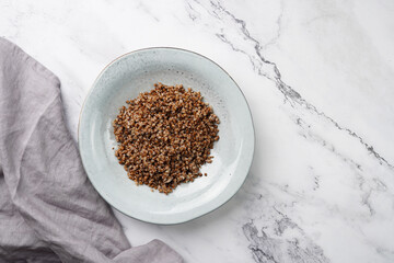 grey porcelain scandi soup bowl with traditional east european dish buckwheat on a marble surface and kitchen towel, top view, copy space
