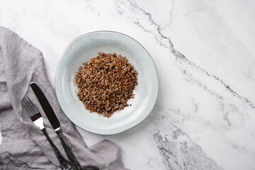 grey porcelain scandi soup bowl with traditional east european dish buckwheat on a marble surface and kitchen towel, top view, copy space
