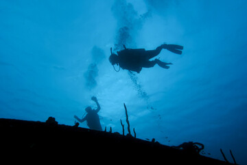 SCUBA diver hover over a shipwreck in silhouette