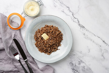 grey porcelain scandi soup bowl with traditional east european dish buckwheat with butter on a marble surface and kitchen towel, top view, copy space