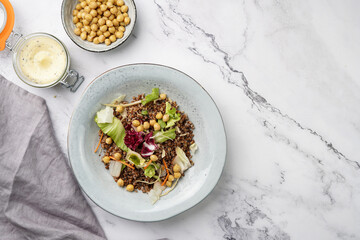 grey porcelain scandi soup bowl with traditional east european dish buckwheat salad with butter and chickpeas on marble surface and kitchen towel, top view, copy space