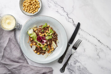grey porcelain scandi soup bowl with traditional east european dish buckwheat salad with butter and chickpeas on marble surface and kitchen towel, top view, copy space