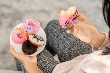 woman hand eating donuts , sugar addiction concept , unhealthy eating sweet food