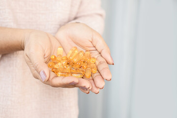 closeup woman hand holding fish oil capsules ,health care and medical concept