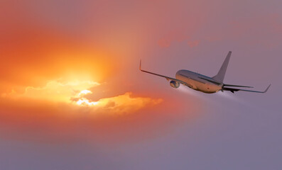 Fototapeta premium White passenger airplane flying away in to sky high altitude during sunset time