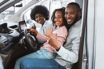 Happy family showing thumbs up at driver seat of car, checking auto salon before buying vehicle, recommending dealership