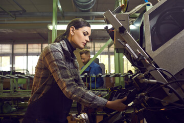 Side view of serious female worker working with special machinery at shoe factory. Woman using...