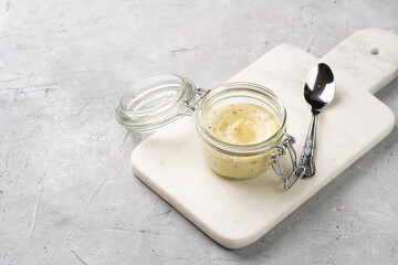 Mason jar with tasty herb butter with grated truffles on scandi plate on grey concrete surface