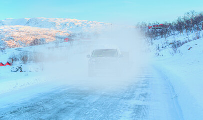 SUV rides on a winter forest road - A car in a snow-covered road among trees and snow hills - Tromso, Norway