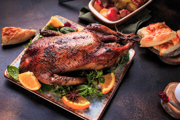 Traditional roasted stuffed Duck. Baked duck with oranges served with sauces, over dark background, top view. 
