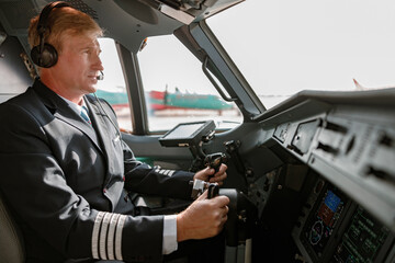 Male pilot in headphones controlling airplane flight
