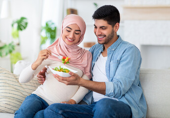 Balanced diet in pregnancy concept. Caring muslim man giving his expectant wife yummy vegetable...