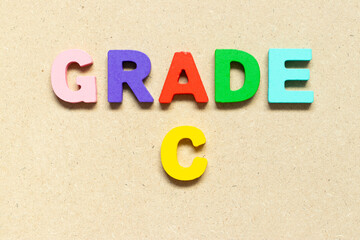Color alphabet letter with word grade C on wood background