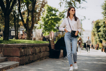 Young woman in white shirt walking outside summer streets