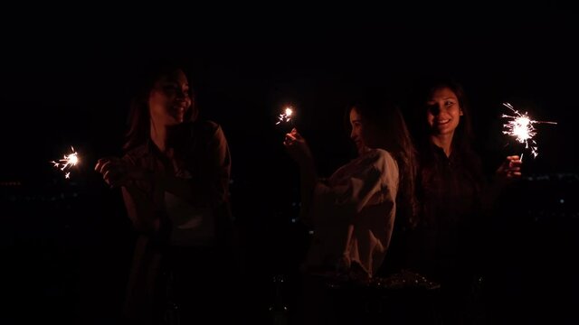 Three young Asian women enjoy playing with sparkle fire.