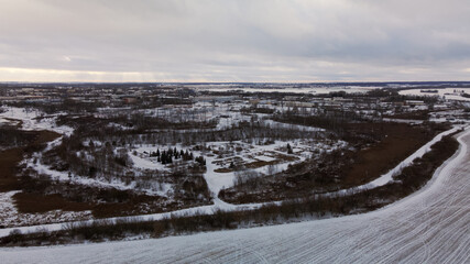 Flying over a snowy field. Traces of agricultural tillage are visible under the snow. Aerial photography.