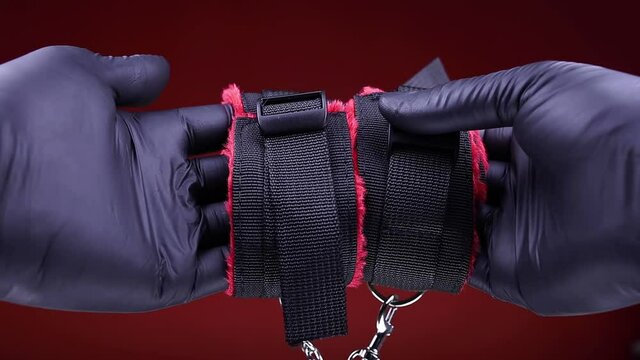 Intimate adult toys for BDSM men's hands in black gloves hold soft handcuffs with straps
