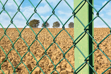Green metal wire mesh against a field or private property