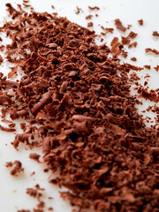 Dark chocolate pieces isolated on white background. Chocolate bar chunks, shavings and cocoa crumbs Top view.