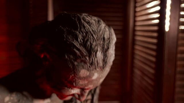 enjoying mud wrap in spa, portrait of laughing lady, hair face and body are covered by clay